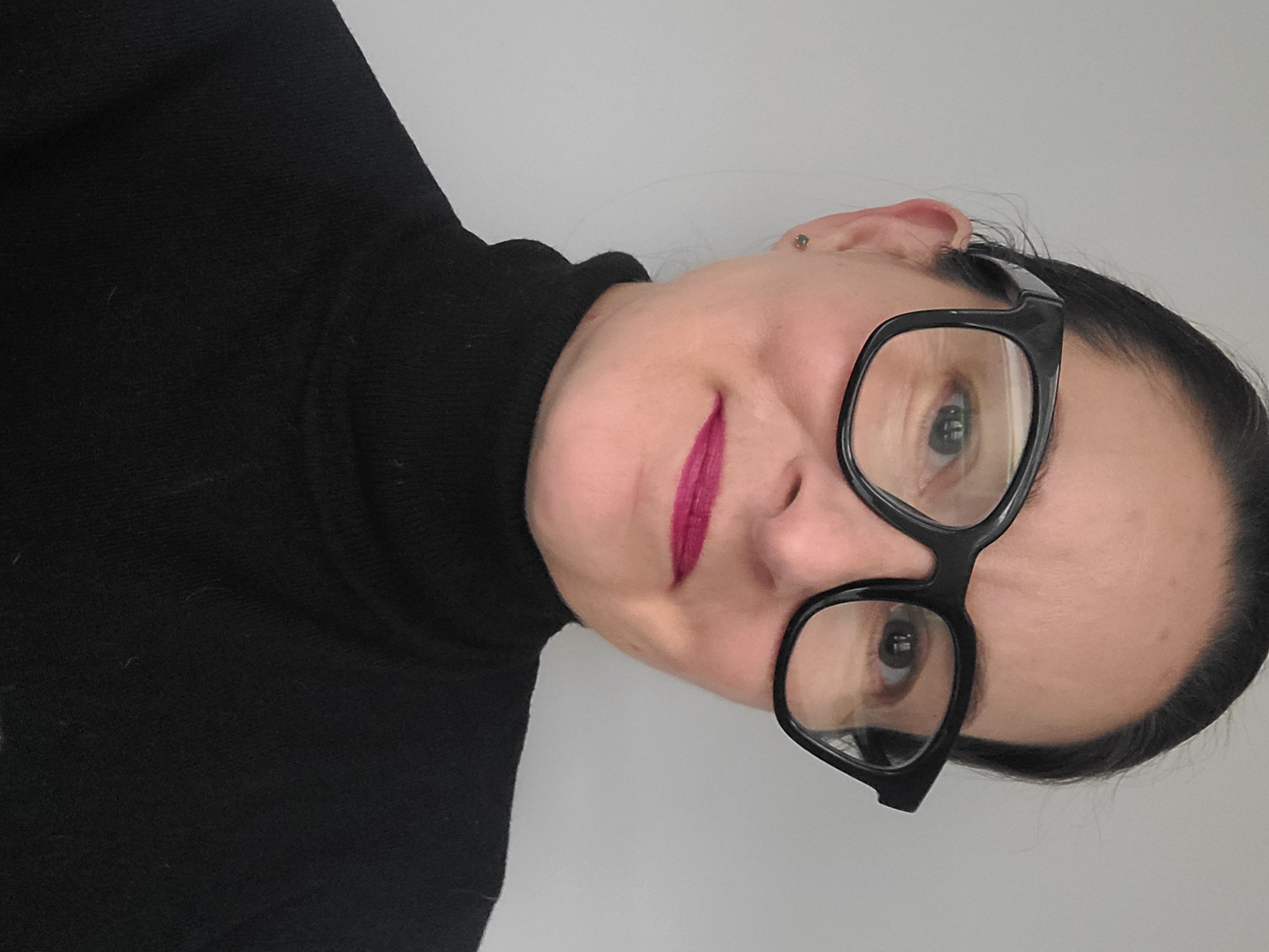 KHG in black-rimmed glasses and a black turtleneck